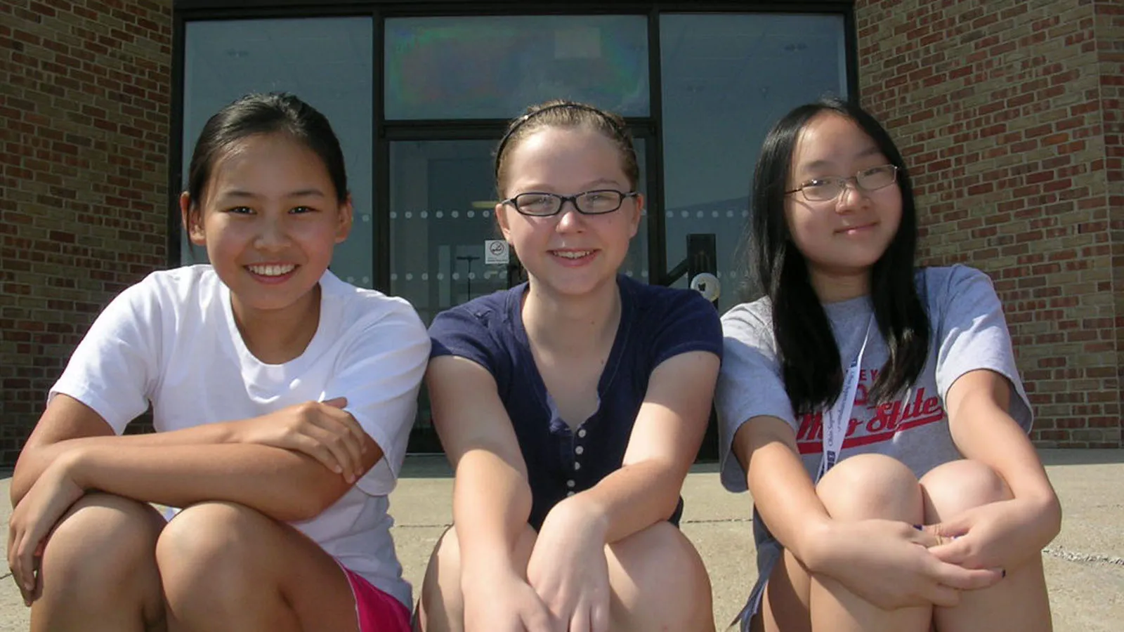 three students seated outside