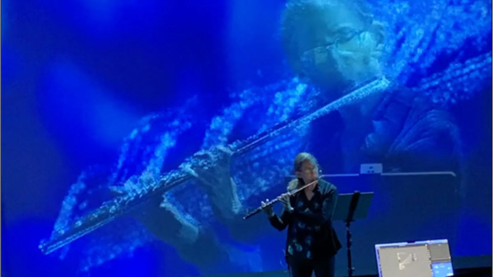 Woman playing flute with blue background