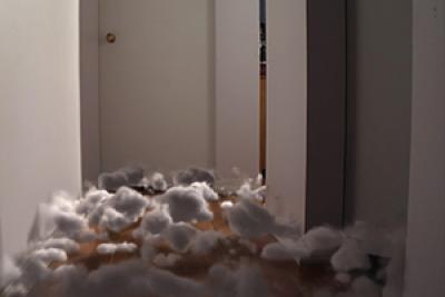 Still from The Approach showing surreal cotton balls on the floor in the hallway of a house