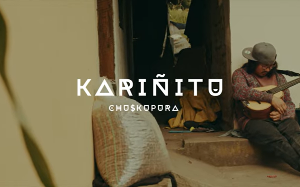 Kariñitu logo against a scene outside of a home where a man sits on the back step with his eyes closed, holding a guitar.
