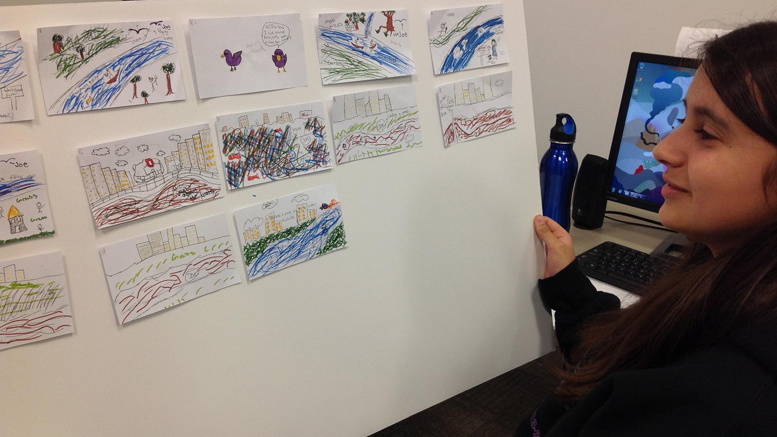 Student showing hand drawn sketches on storyboard