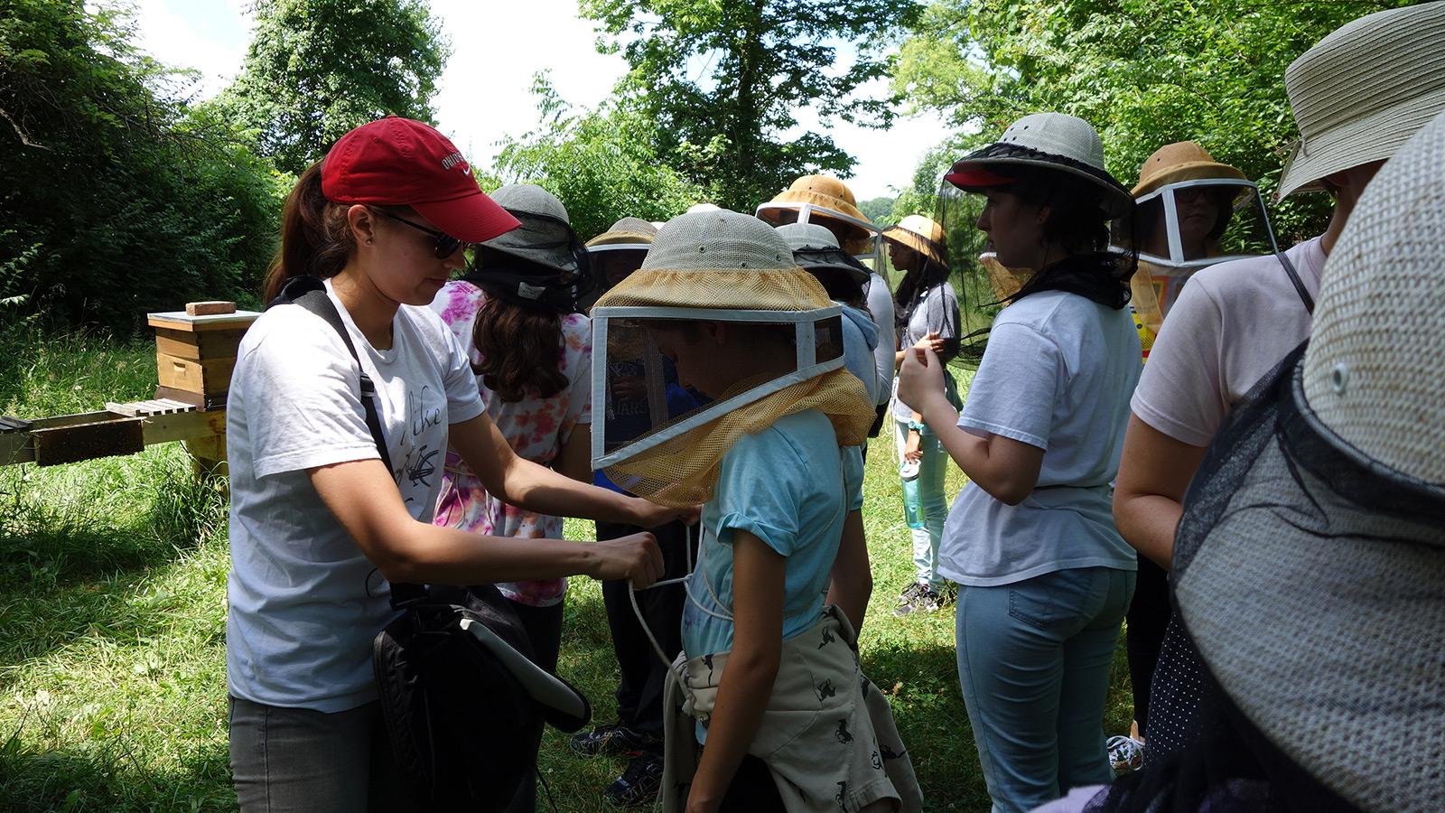 Students putting on beekeeping hats at apiary visit